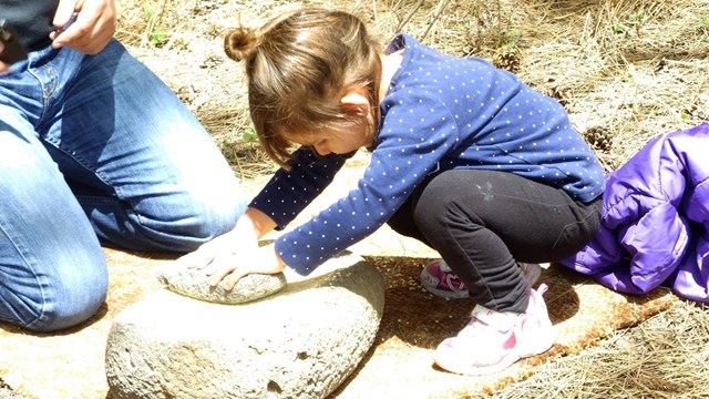 A Junior Ranger tries out a metate.