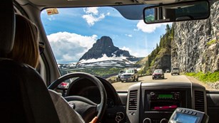 View of road and rock wall looking over driver's shoulder out windshield