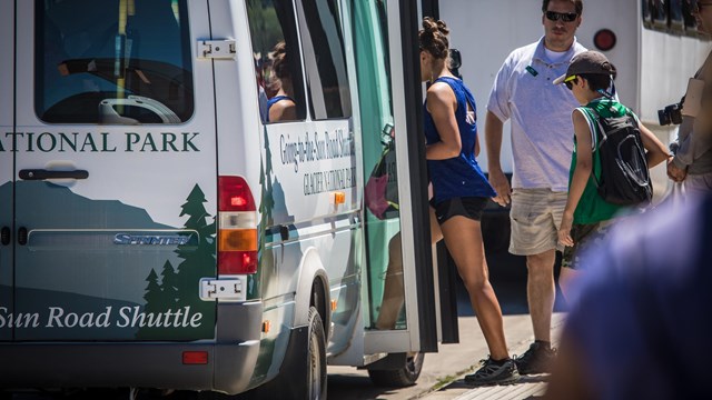 People walk onto a shuttle bus. 