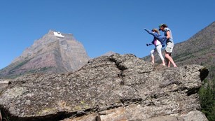 Child and adult hike across rock in wind