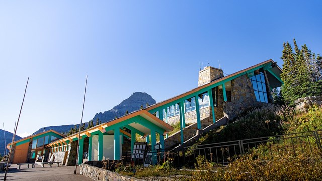 The bright sun shines on a modern-looking building with a pointed roof. 