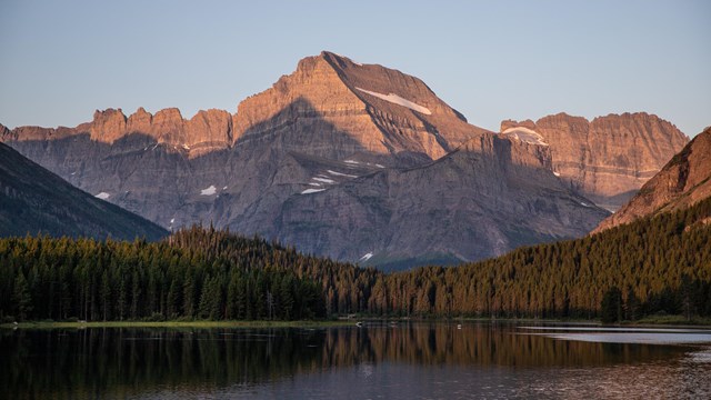 A landscape view of the Many Glacier Valley at sunrise. 