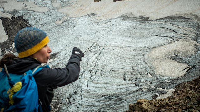 A person points at a glacier.