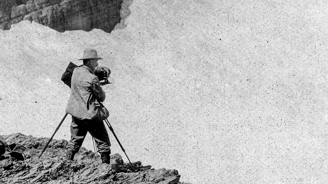 Historic image of a person photographing a glacier