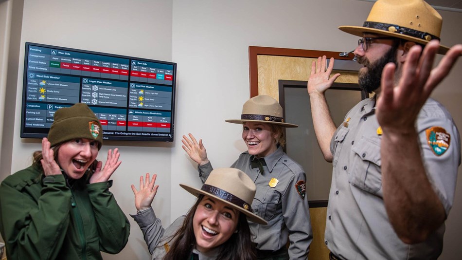 Four rangers smile around a screen.