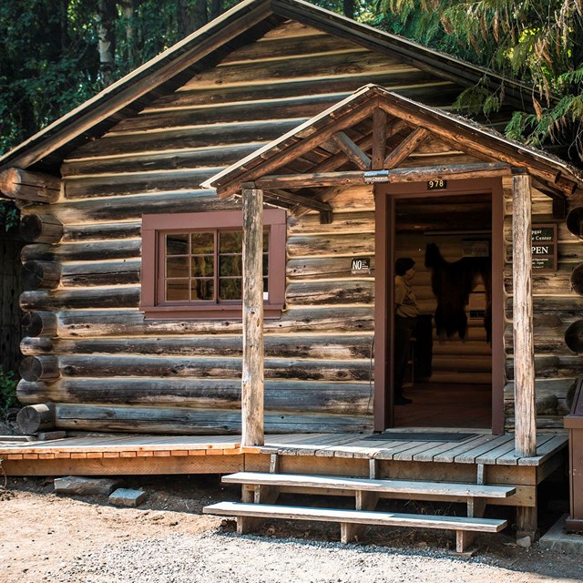 View of a rustic log cabin with its door open.
