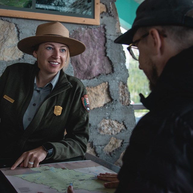 Visitor talks to a park ranger at an outside desk.