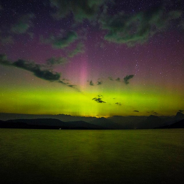 beams of light, colors, and clouds in night sky over lake