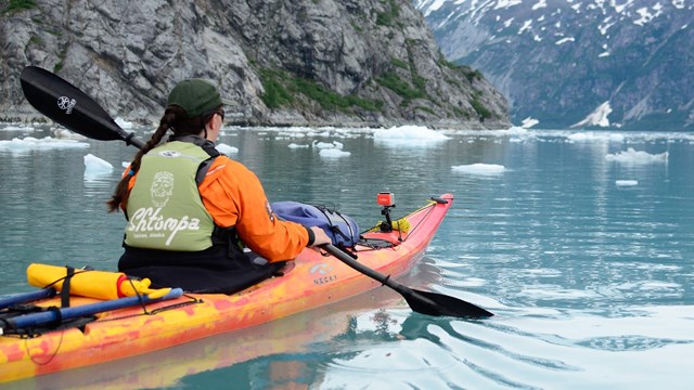 a kayaker paddles through icy waters in Glacier Bay
