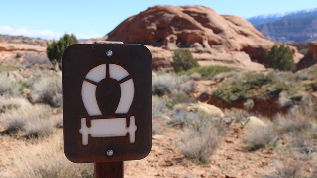 wagon emblem on sign with sandstone butte and sagebrush country behind