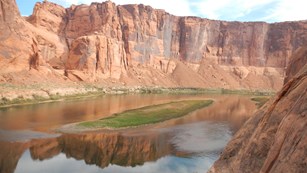 River, cliffs, clear sky. Cliffs reflected in water.