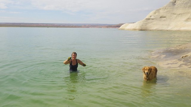 person and dog waist deep in murky lake