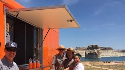 Smiling people and rangers in front of an orange food truck