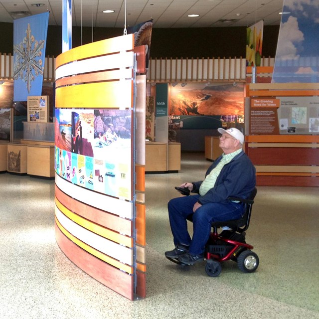 Man in wheelchair studies visitor center exhibits