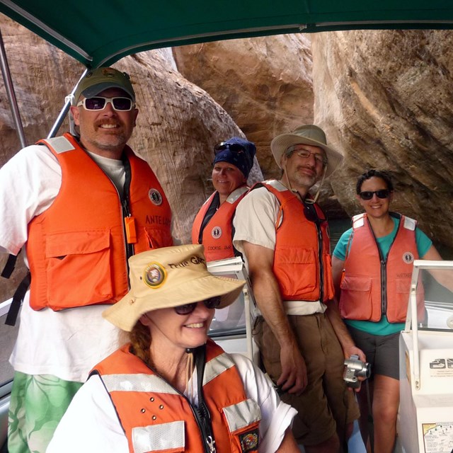 Group wearing lifejackets on boat tucked in narrow canyon