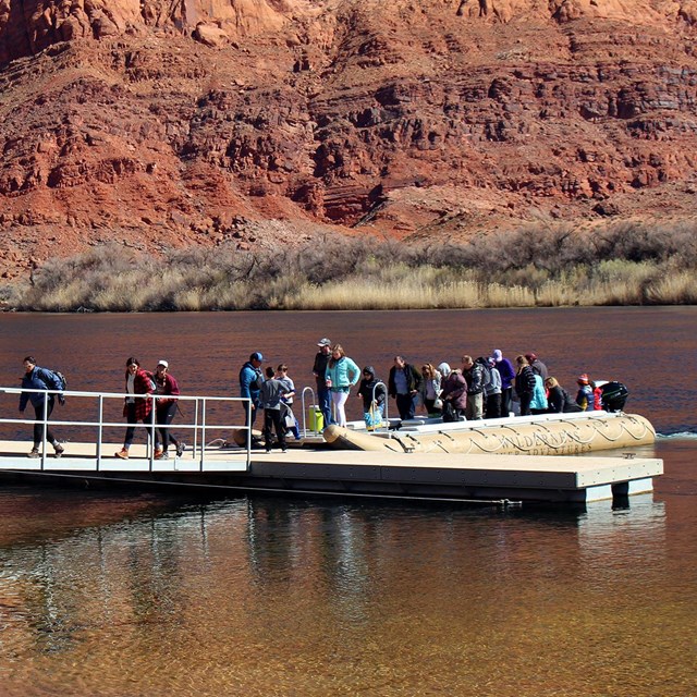 Customers file off of a large motorized raft at the Lees Ferry boat dock