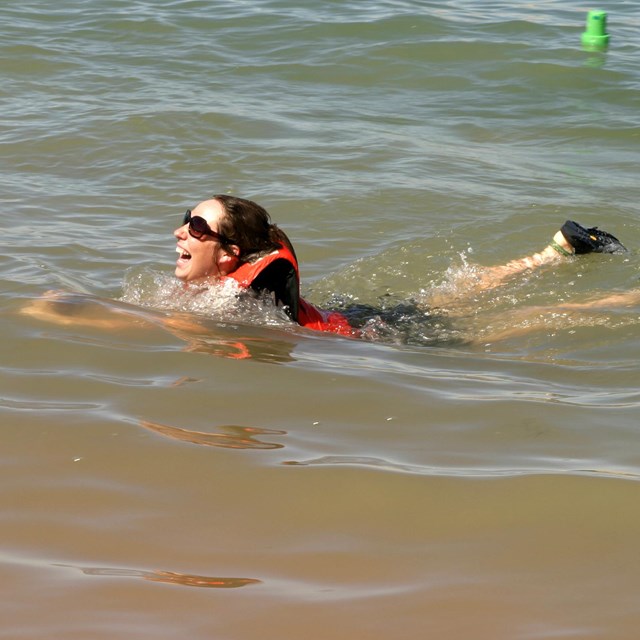 Woman in life jacket treads water