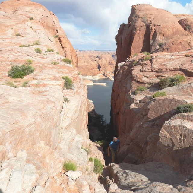 Hiker walks through a narrow opening in a cliff