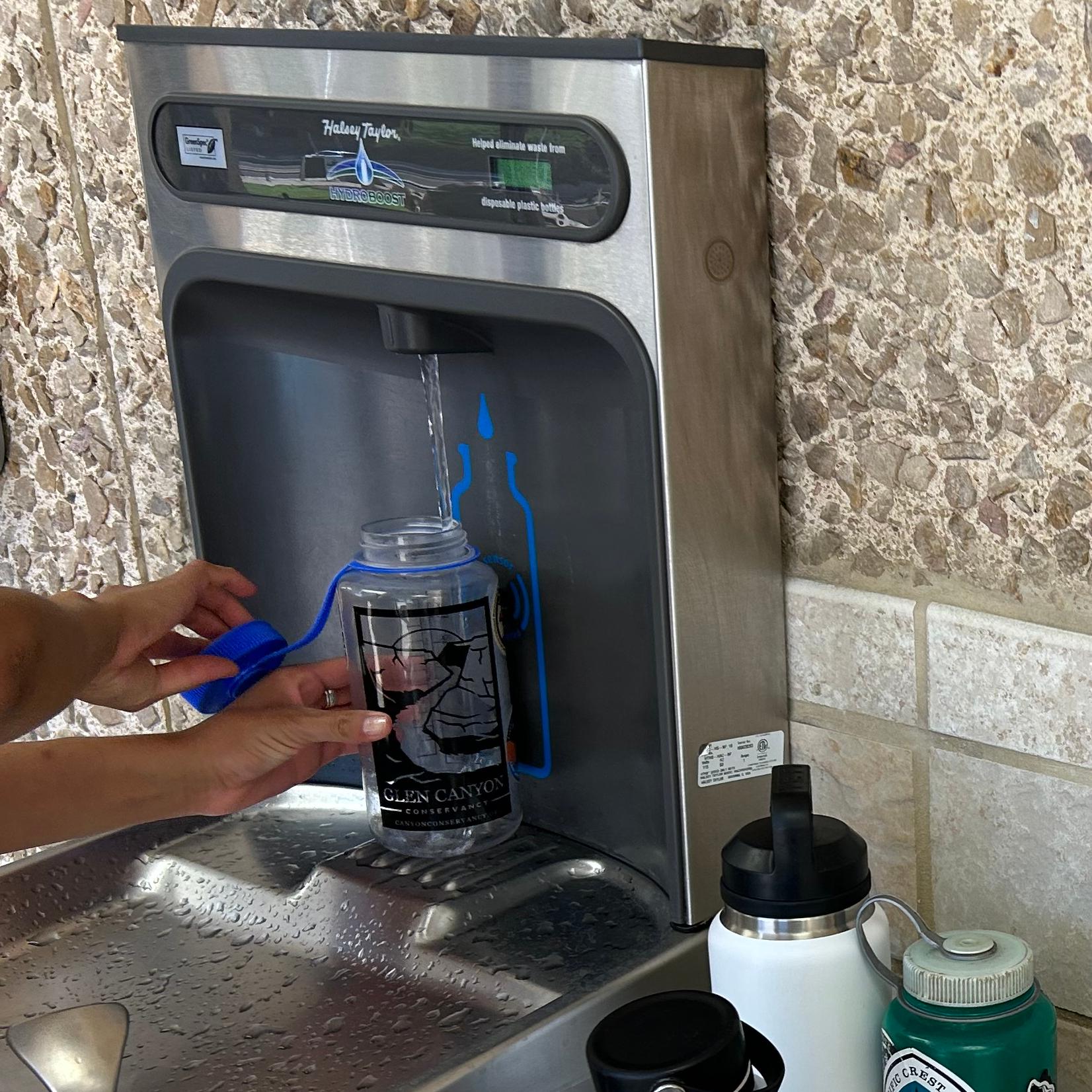 a water bottle filling station is used to refill a few water bottles