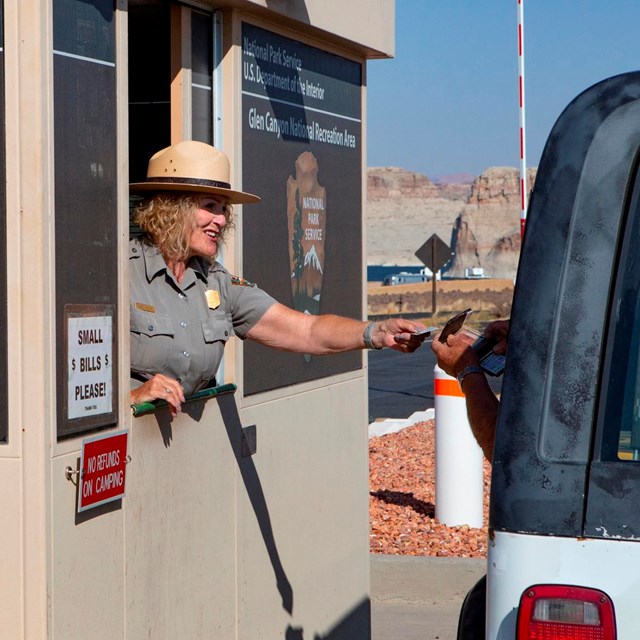 Park Ranger in fee booth reaches out to car