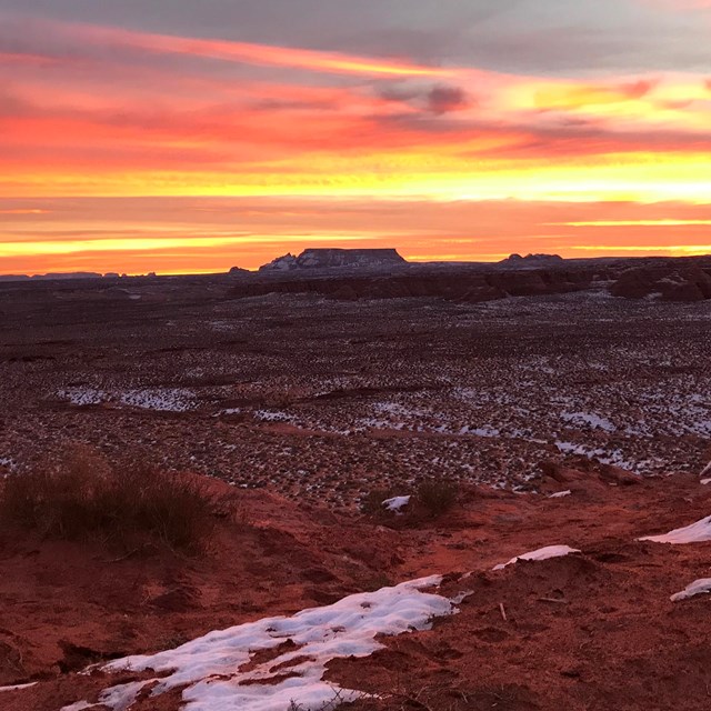 Sunrise over red sand with patchy snow