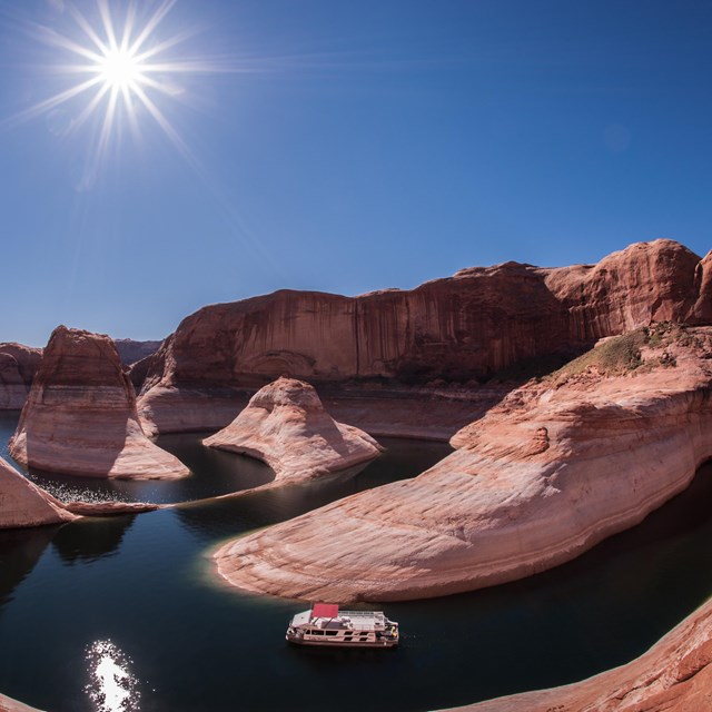 A houseboat winds through high cliffs.