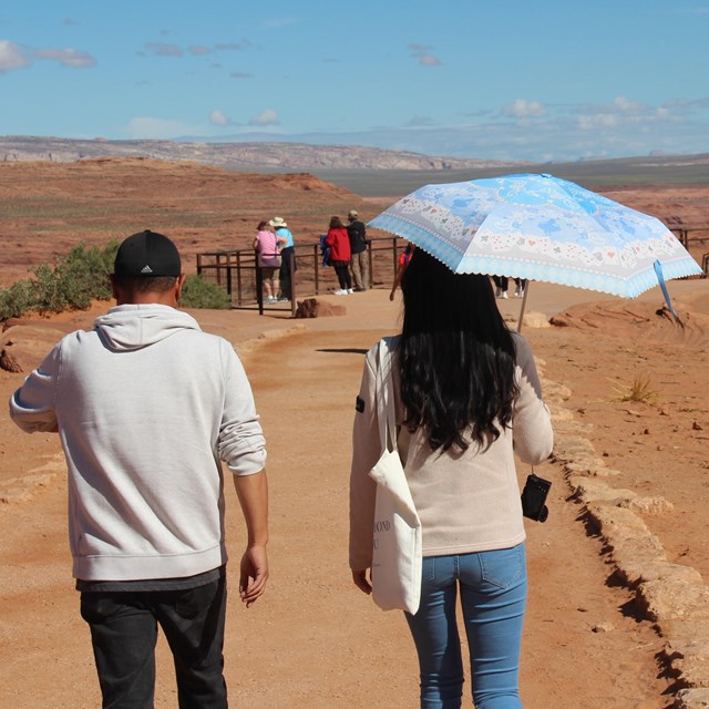 Hiker on trail uses a sun parasol