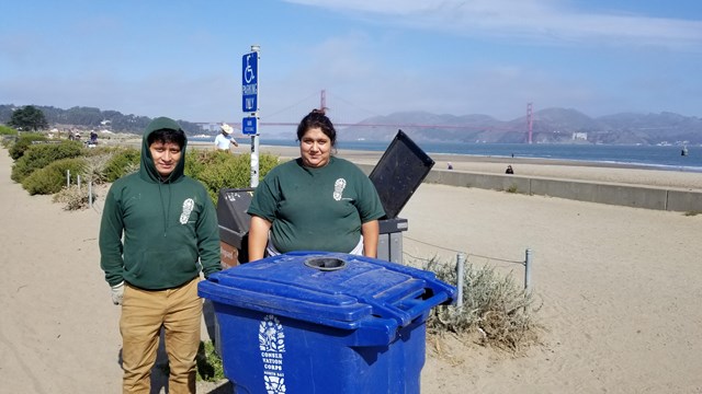 Two CCNB crews stand with a recycling bin along the Crissy Field Promenade