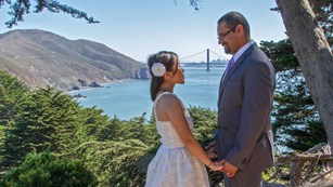 A couple in wedding attire with the Golden Gate Bridge behind