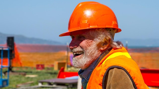 man in construction uniform, smiling, outside