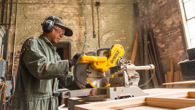 man in uniform, holding chain saw, doing woodwork inside old brick building