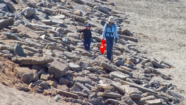 woman and child walking along rocks. woman is holding plastic bag