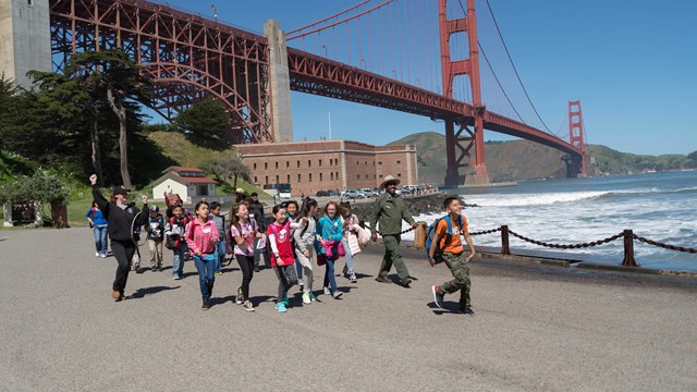 Group of youth walk away from Fort Point with two ranger