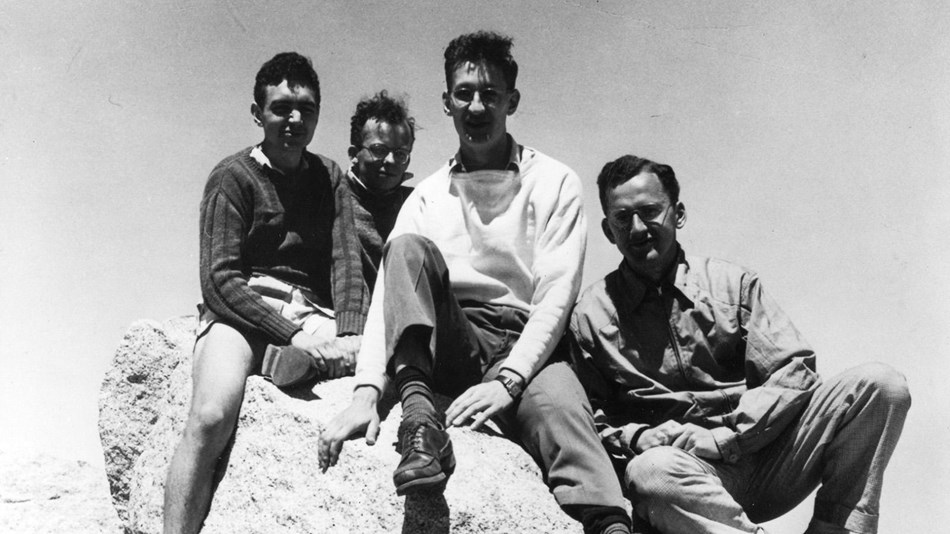 A young Clyde Wahrhaftig (center front) and friends sit on rocks outdoors