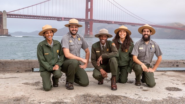 group of rangers in front of gg bridge holding education items