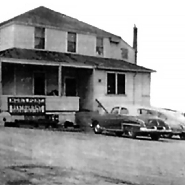 1950's photo of a house with a parked cars in front