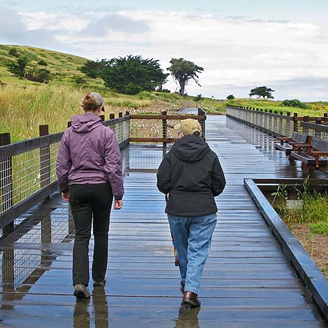 Two visitors take the boardwalk towards Mori Point.