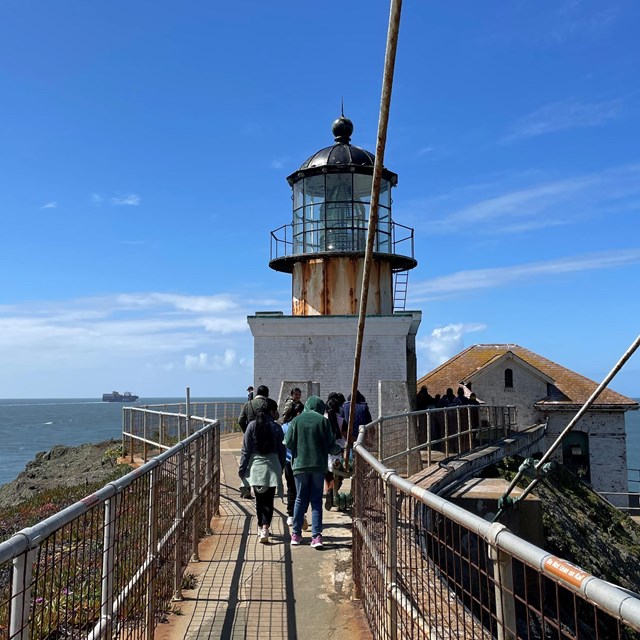 Students walk across a bridge leading to the Point Bonita Lighthouse
