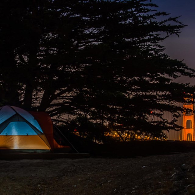 tent on ground with lit golden gate bridge in background