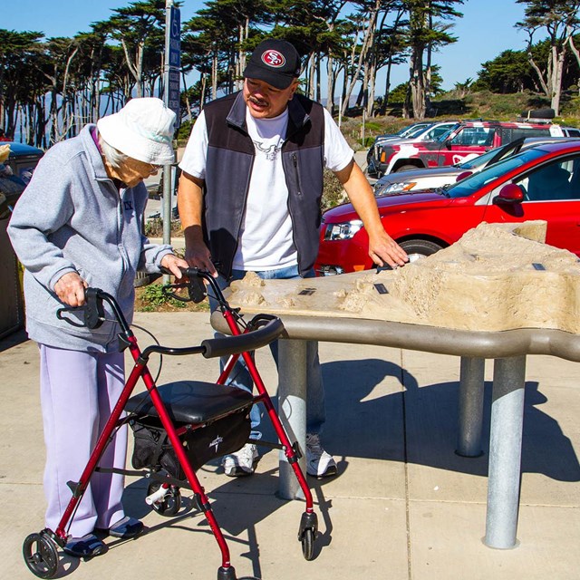 visitor using a walker examines trail model