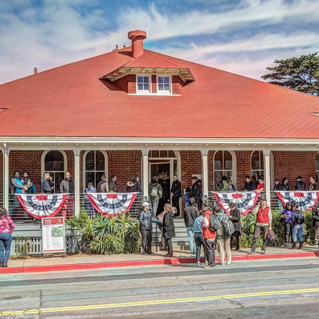 red brick building with people on porch and front lawn