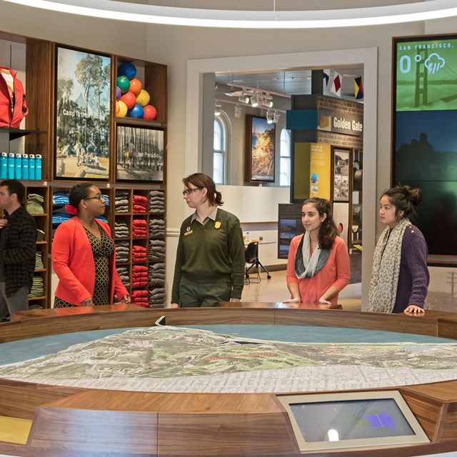 A ranger and visitors look at a 3-D map of the Presidio in the visitor center