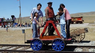 A family enjoying a handcar ride. 