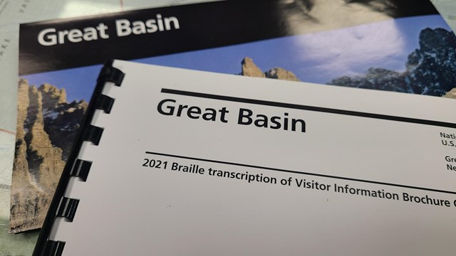 A park brochure made in braille stating "Great Basin" lies on top of a standard brochure