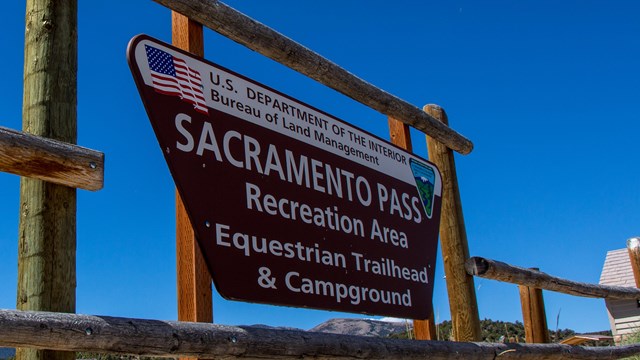 Brown sign with white lettering on fence posts