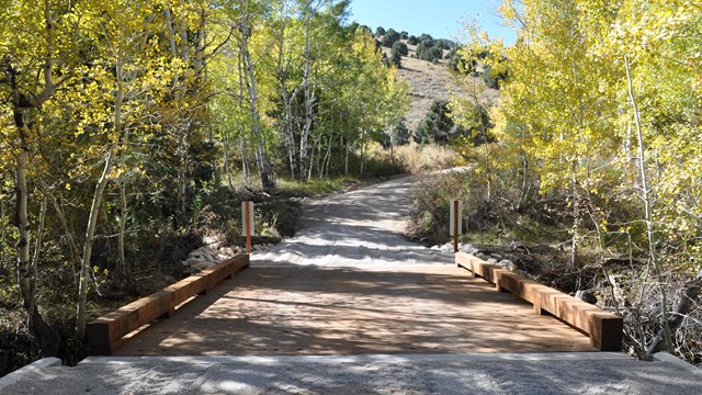 Gravel road at Strawberry Creek joining with a wooden bridge over a creek.