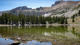 A still lake reflecting the mountains in the background.