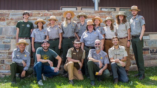 Park Rangers and intern lined up in front of a grey wall 