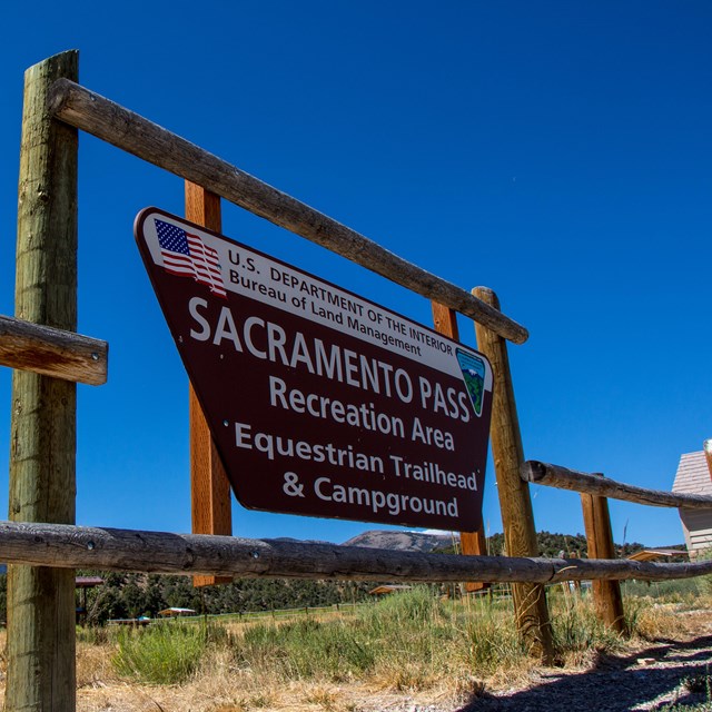 Brown sign with white lettering on fence posts