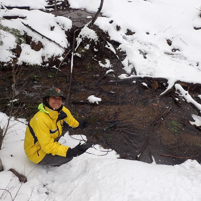 Scientist measures spring water quality during snowstorm with a portable probe.